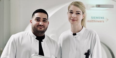 Zwei Mitarbeitende vor einem CT in der Arbeitskleidung in der Röntgenabteilung